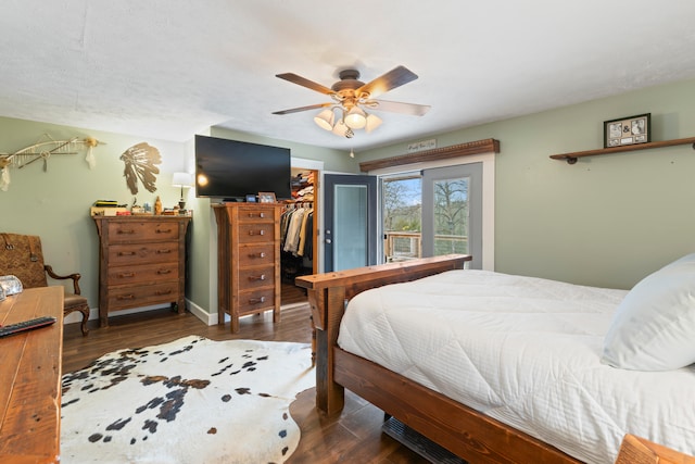 bedroom with a walk in closet, ceiling fan, a closet, and dark hardwood / wood-style flooring