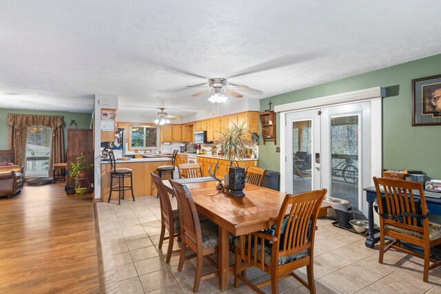 dining room featuring ceiling fan, french doors, light tile patterned flooring, and a textured ceiling