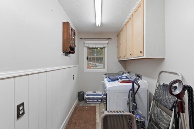 washroom with cabinets, a textured ceiling, and washing machine and dryer