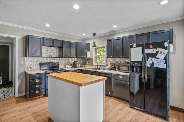 kitchen featuring pendant lighting, wood counters, black appliances, sink, and light wood-type flooring