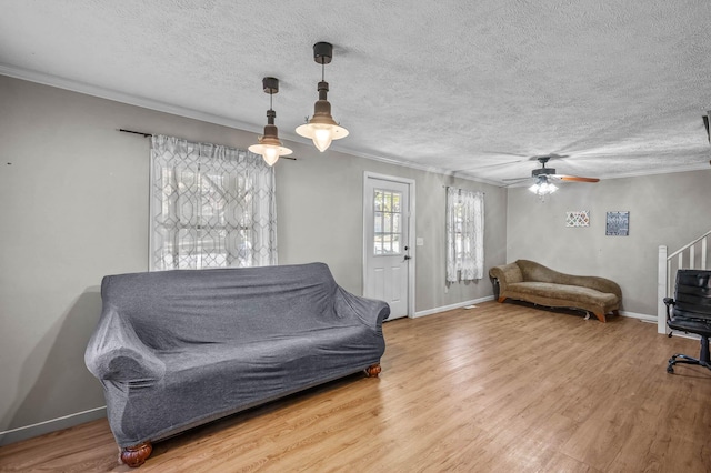 living room featuring a textured ceiling, hardwood / wood-style flooring, ceiling fan, and ornamental molding