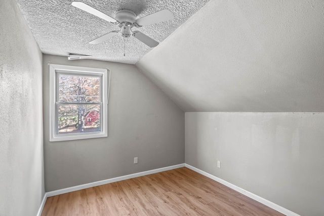 bonus room featuring ceiling fan, vaulted ceiling, a textured ceiling, and light hardwood / wood-style flooring