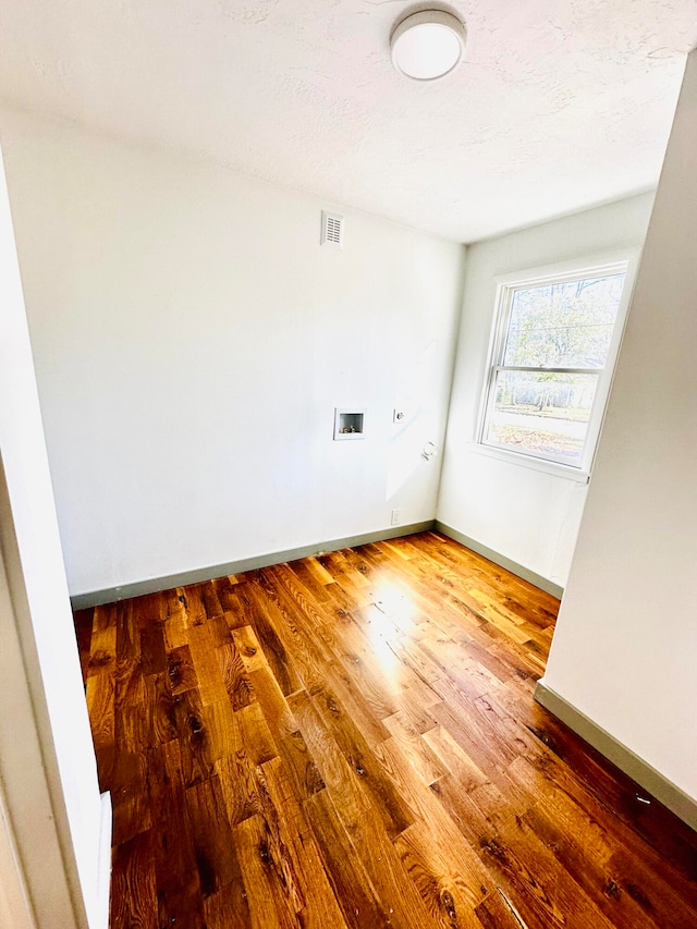 empty room with a textured ceiling and hardwood / wood-style flooring