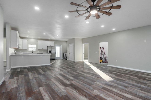 unfurnished living room featuring dark hardwood / wood-style floors, ceiling fan, and sink