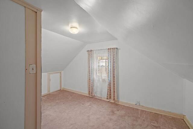 additional living space with light colored carpet and lofted ceiling