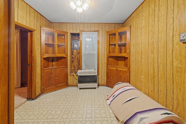 bedroom featuring heating unit, wooden walls, and ceiling fan