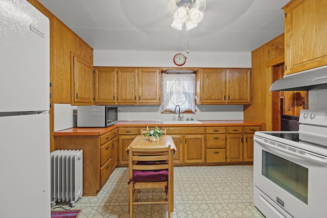 kitchen featuring ceiling fan, radiator heating unit, sink, backsplash, and white appliances