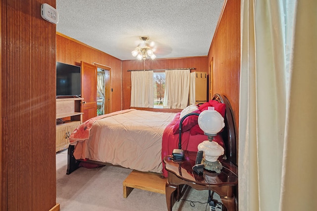 carpeted bedroom featuring ceiling fan, wood walls, and a textured ceiling