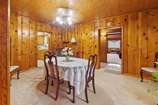 carpeted dining room featuring sink, ceiling fan, and wood walls