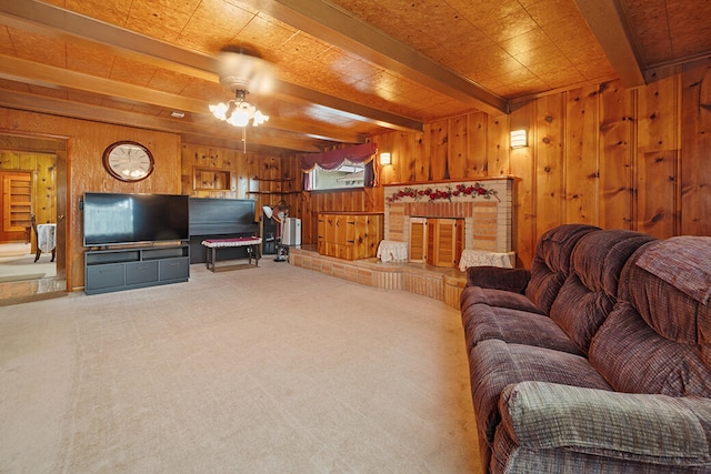 carpeted living room featuring wooden walls, a fireplace, beamed ceiling, and ceiling fan