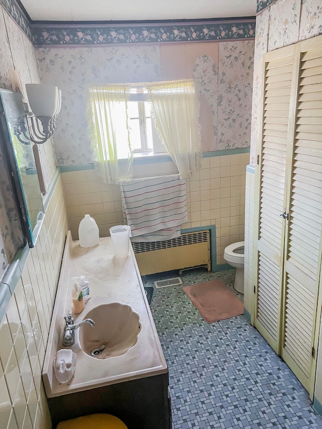 bathroom featuring radiator heating unit, vanity, toilet, and tile walls