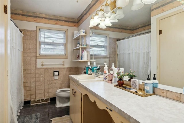 bathroom with toilet, vanity, tile patterned floors, and tile walls