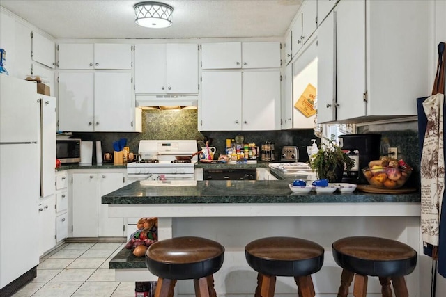 kitchen with white cabinetry, white appliances, and a breakfast bar area