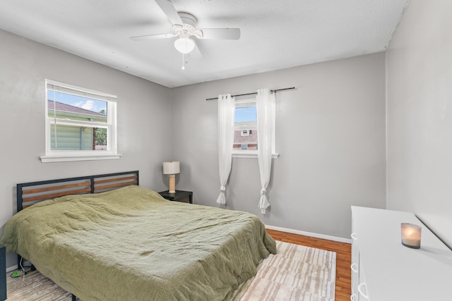 bedroom with multiple windows, ceiling fan, wood-type flooring, and a textured ceiling