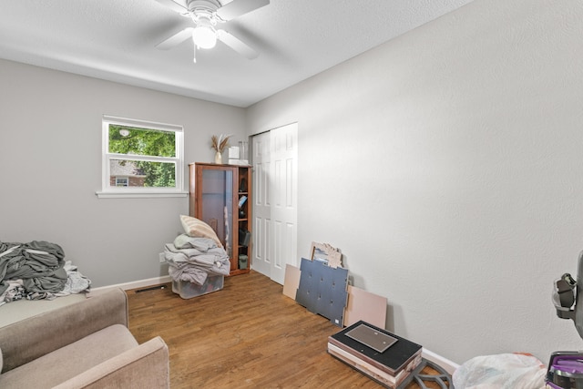 living area with ceiling fan and wood-type flooring