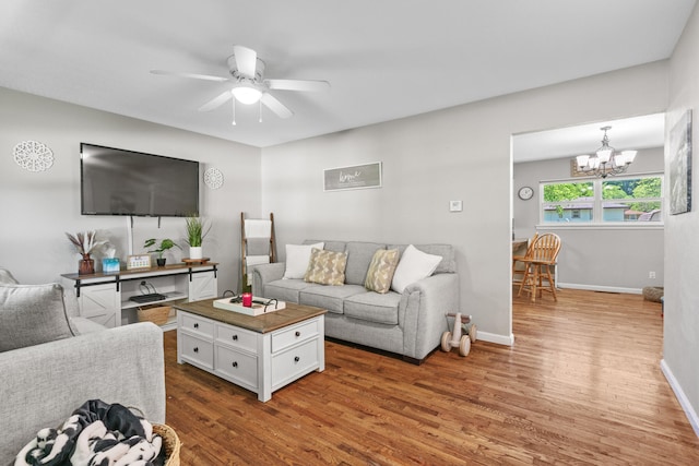 living room featuring ceiling fan with notable chandelier and hardwood / wood-style flooring