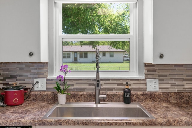 room details with tasteful backsplash, sink, and white cabinets