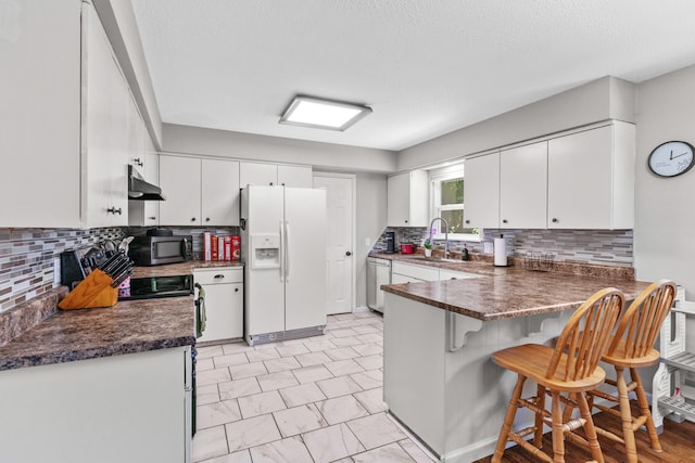 kitchen featuring white cabinetry, sink, stainless steel appliances, kitchen peninsula, and decorative backsplash