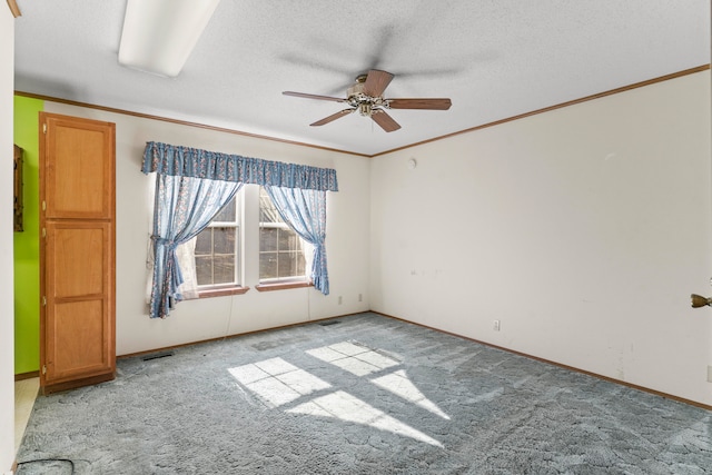 carpeted spare room featuring ceiling fan, a textured ceiling, and ornamental molding