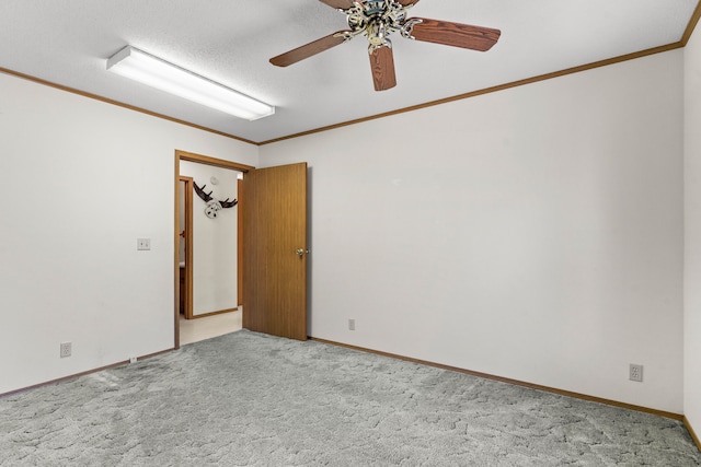 carpeted empty room featuring a textured ceiling, ceiling fan, and crown molding