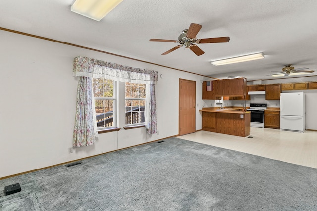 kitchen with white appliances, light carpet, ceiling fan, a textured ceiling, and kitchen peninsula