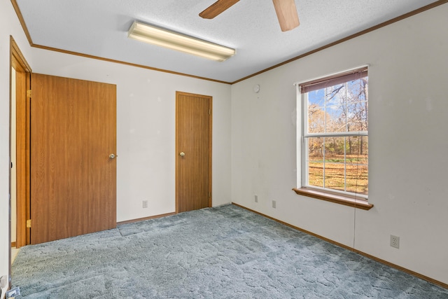 unfurnished bedroom featuring ceiling fan, light colored carpet, a textured ceiling, and crown molding