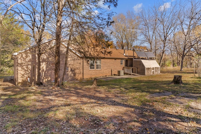 back of property featuring central AC, an outdoor structure, and a lawn