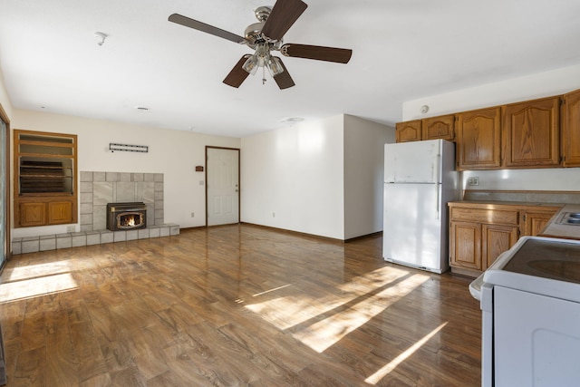 kitchen with a wood stove, stove, white fridge, and dark wood-type flooring