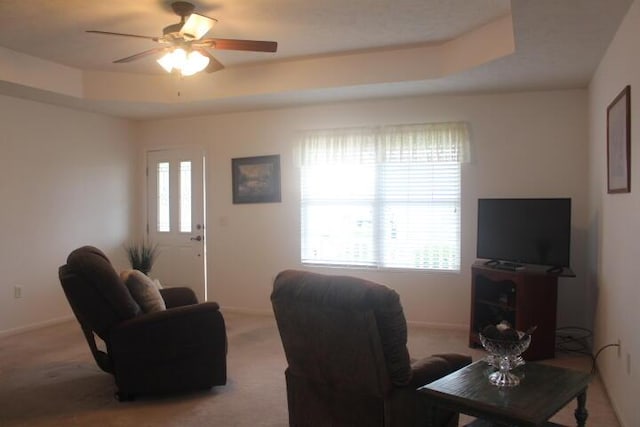 carpeted living room featuring ceiling fan, a healthy amount of sunlight, and a raised ceiling