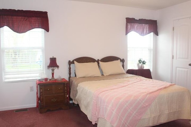 bedroom with dark colored carpet and multiple windows