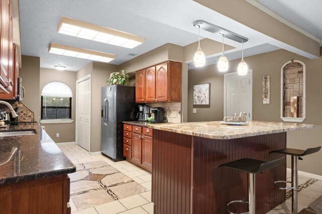 kitchen with backsplash, sink, light tile patterned floors, light stone counters, and stainless steel appliances