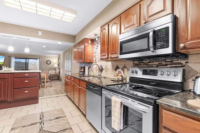 kitchen with sink, decorative backsplash, decorative light fixtures, light hardwood / wood-style floors, and stainless steel appliances