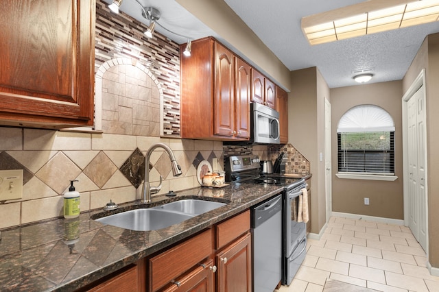 kitchen with appliances with stainless steel finishes, backsplash, dark stone counters, a textured ceiling, and sink