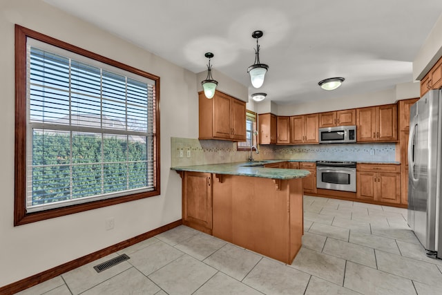 kitchen with kitchen peninsula, plenty of natural light, pendant lighting, and appliances with stainless steel finishes