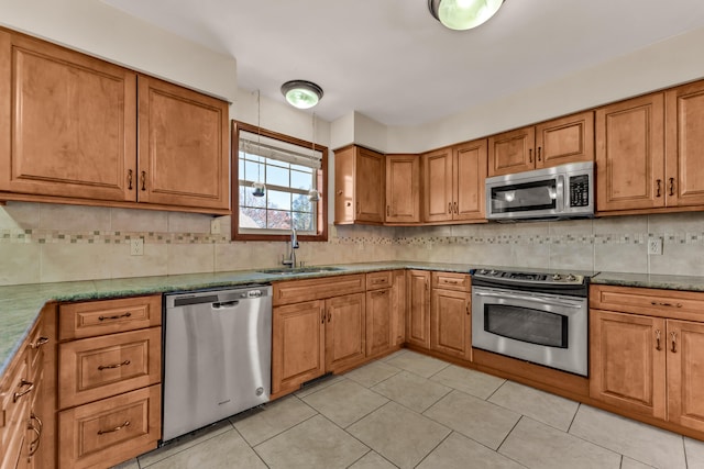 kitchen with sink, tasteful backsplash, stone countertops, light tile patterned floors, and appliances with stainless steel finishes