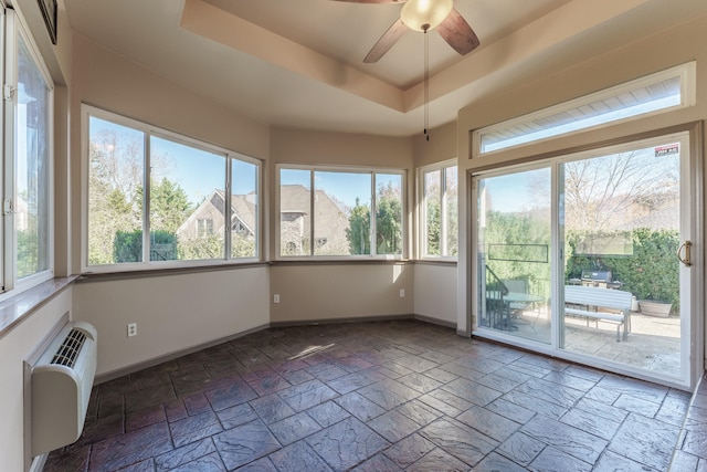 unfurnished sunroom featuring a tray ceiling, a wealth of natural light, and ceiling fan