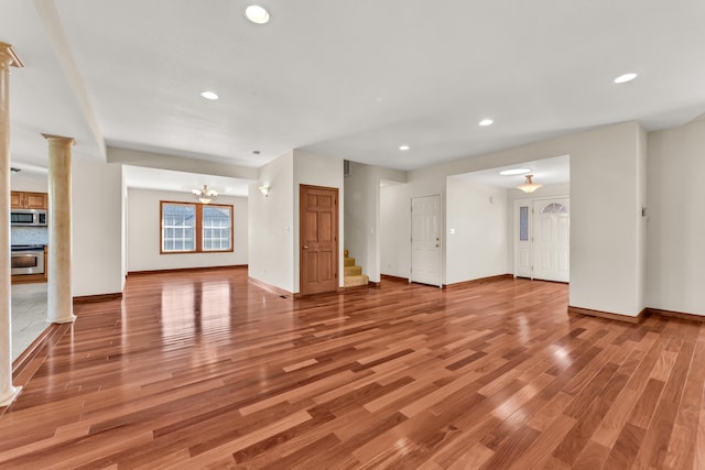 unfurnished living room with a notable chandelier and light wood-type flooring