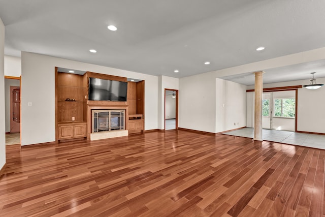 unfurnished living room featuring light wood-type flooring and decorative columns