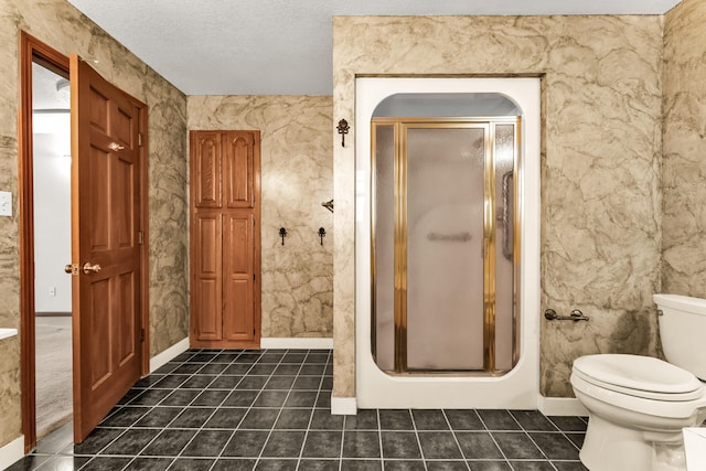 bathroom featuring tile patterned floors, toilet, a shower with shower door, and a textured ceiling