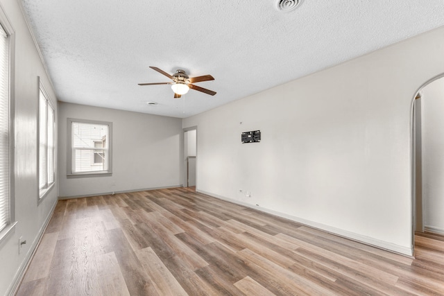 unfurnished room featuring ceiling fan, light wood-type flooring, and a textured ceiling