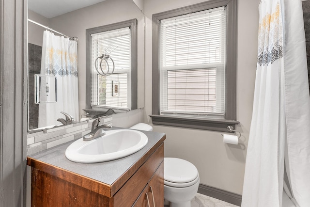 bathroom with decorative backsplash, vanity, a healthy amount of sunlight, and toilet