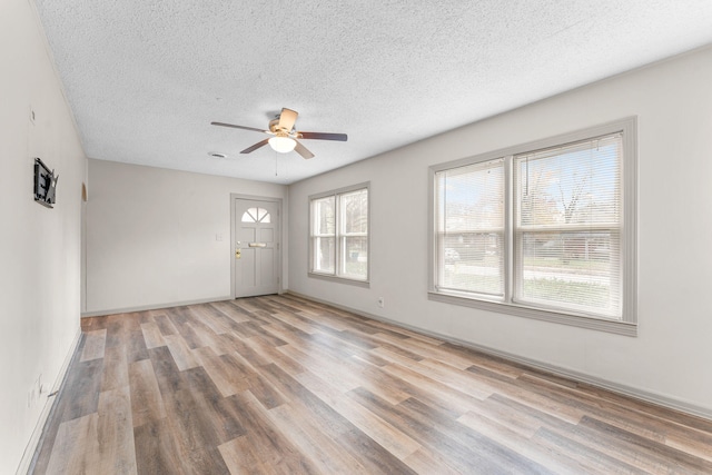 empty room with a textured ceiling, light hardwood / wood-style floors, and ceiling fan