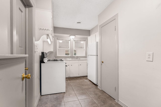 kitchen featuring white cabinetry, sink, a textured ceiling, white appliances, and light tile patterned flooring