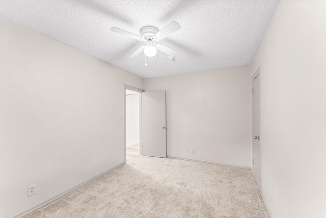 spare room featuring a textured ceiling, ceiling fan, and light carpet