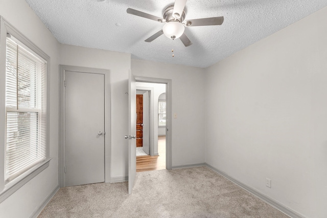 unfurnished bedroom with multiple windows, ceiling fan, and a textured ceiling