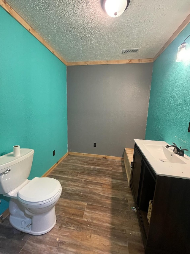 bathroom with hardwood / wood-style floors, vanity, toilet, and a textured ceiling