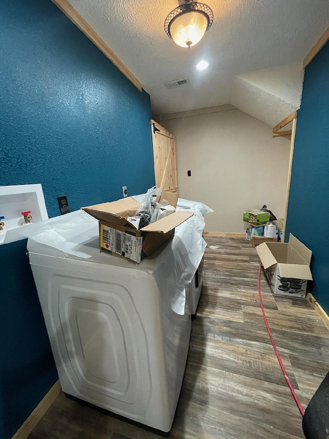 clothes washing area with a textured ceiling, dark hardwood / wood-style floors, and independent washer and dryer