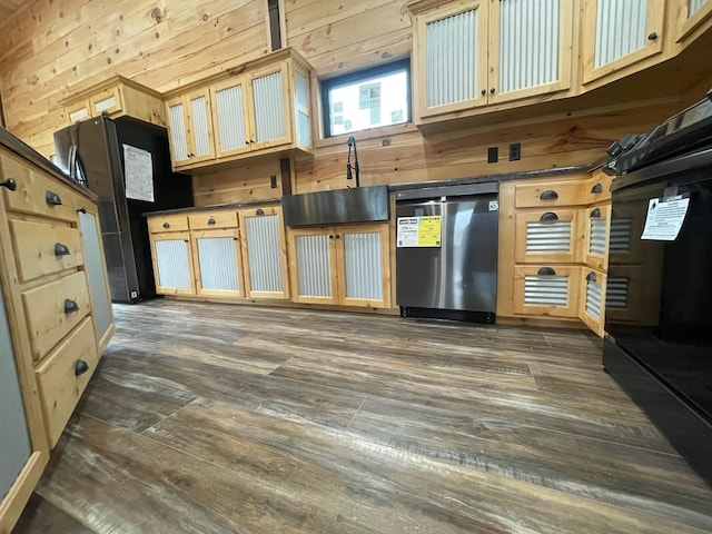 kitchen with black fridge, wooden walls, and stainless steel dishwasher