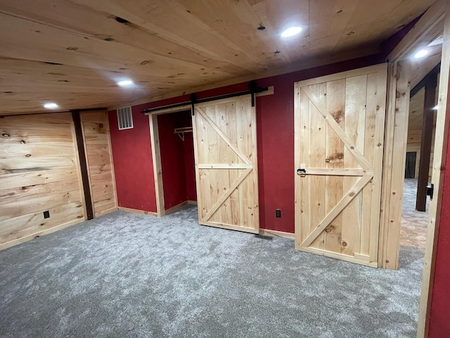 interior space featuring a barn door, wooden ceiling, and dark carpet