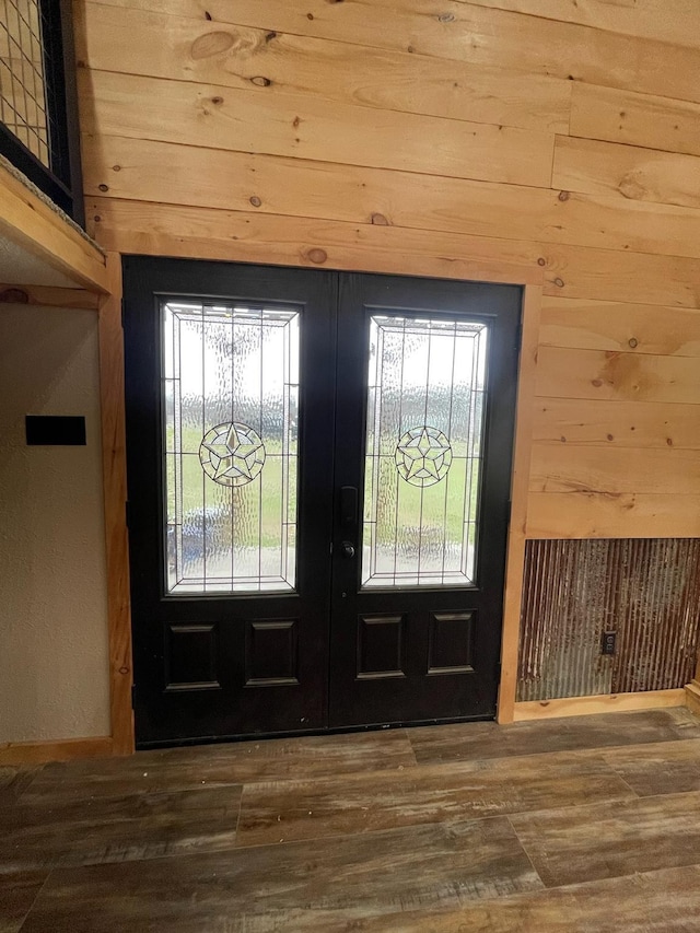 entryway featuring french doors, dark wood-type flooring, a healthy amount of sunlight, and wood walls